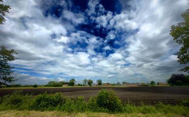 Obraz premium A stunningly picturesque view of a charming rural field beneath a captivating sky showcasing dynamic cloud patterns