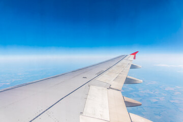 View from the airplane window at a beautiful cloudy sky and the airplane wing