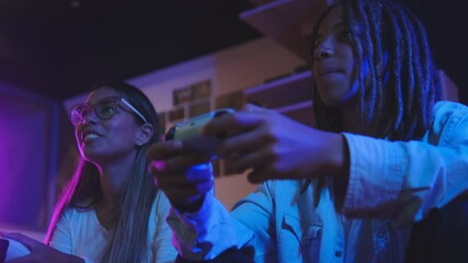 Friends doing a high five while playing, on the sofa in the living room, having fun playing video games together at home. Concept Gaming streaming