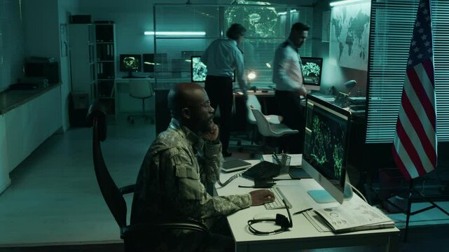 Medium full timelapse of diverse, multiethnic male and female military staff in uniform working with satellite intelligence data on computers in command center, walking around and discussing reports