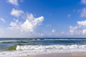 Waves crashing on the shore under a clear blue sky during daylight on a tranquil beach
