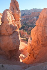 A vibrant view of Bryce Canyon's towering red rock hoodoos, showcasing unique geological formations under a clear blue sky. The natural light accentuates the rugged textures and warm desert tones.