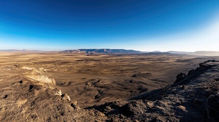 Obraz premium A panoramic view of a vast, arid landscape under a clear blue sky.