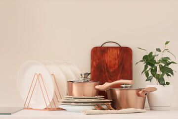 Dishware with cutting board and houseplant on table against white background. Closeup