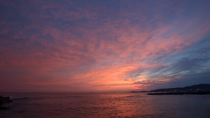 Aerial view of a plane flying low over the ocean during a stunning sunset, with the sun dipping into the water.