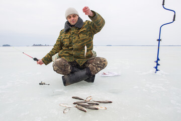 A European man fishes on the ice of a frozen lake.