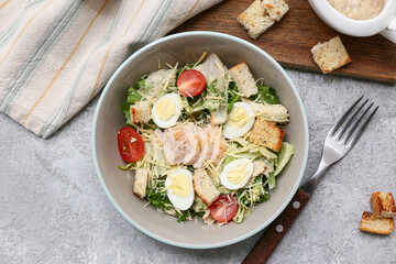 Bowl with tasty chicken Caesar salad on grey background
