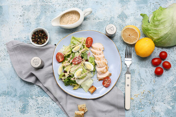 Plate with tasty chicken Caesar salad and ingredients on blue background