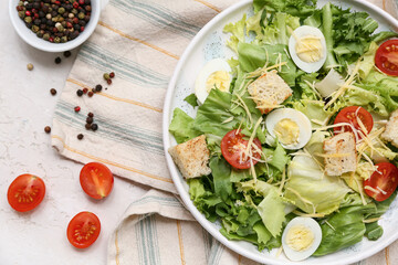 Plate with tasty Caesar salad and bowl of peppercorn on white background
