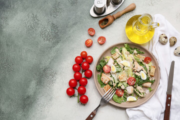 Plate with tasty chicken Caesar salad, tomatoes and oil on grunge background