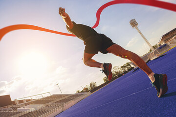 Fit young man running sprinting to red finish line at the racetrack. Finisher, marathon runner...