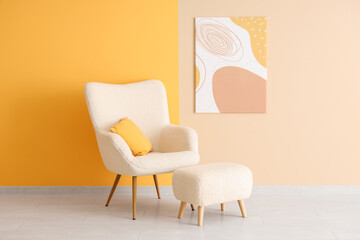 White armchair, pouf and picture on colorful wall in room