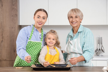 Little girl with her mom and granny preparing cookies in kitchen