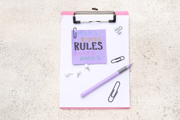 Clipboard with words RULES and paper clips on grunge background