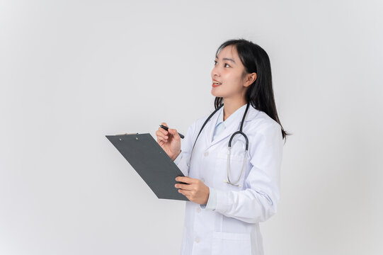 An Asian female doctor in a uniform holding a medical clipboard, looking upward at an empty space.