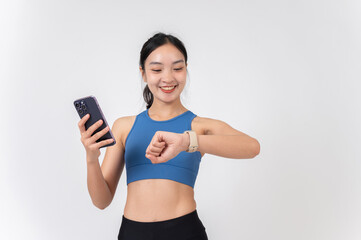 A smiling young Asian woman in sportswear looking at her smartphone while holding her smartphone.