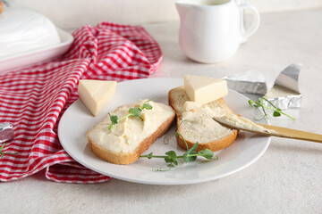Plate with fresh bread, triangles of tasty processed cheese and micro green on light table
