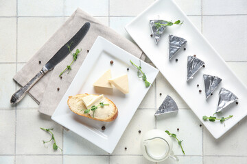 Composition with triangles of tasty processed cheese, bread, micro green and spices on light tile...