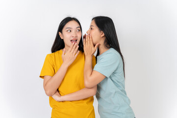 Naklejka premium Two Asian female friends whispering a gossip secret to each other, with one amazed by the story.