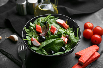 Plate of salad with crab sticks, spinach, black olives and ingredients on grey grunge background © Pixel-Shot