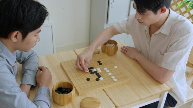 Asian young men playing board game Go during competition in community.