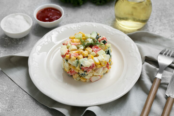 Plate of salad with crab sticks, corn and cucumber on grey grunge background