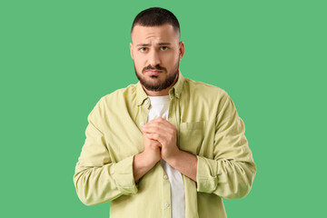 Apologetic young man on green background