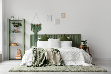 Modern bed with green plaid and shelving unit in interior of bedroom