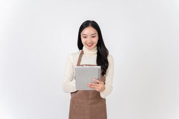 A smiling female waitress or coffee shop staff in a brown apron writes order in her digital tablet.