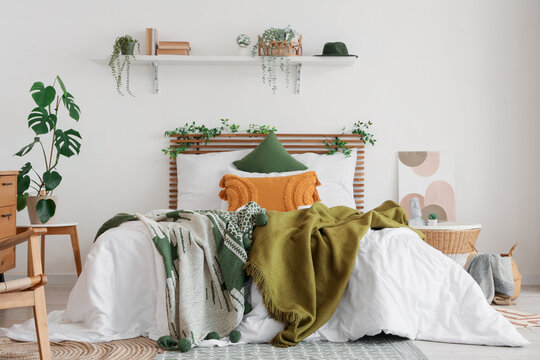 Stylish interior of modern bedroom with green blankets on bed