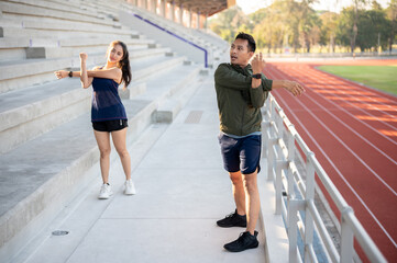 Obraz premium Two Asian friends stretching their body on a stadium, exercising together in the morning.
