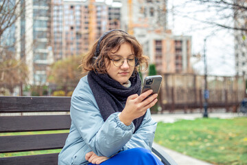 Fototapeta premium A teenage girl uses a phone in the city. Girl in the city. Technology concept.