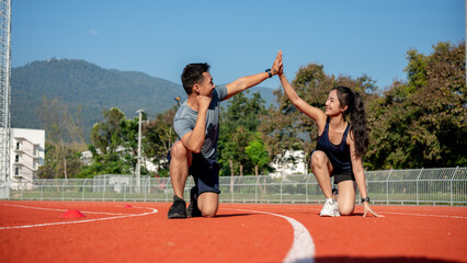 Obraz premium Two runners give high five while getting ready to run on a running track, training at a stadium