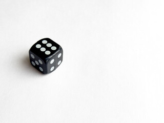 Single black dice with white dots on blank white background