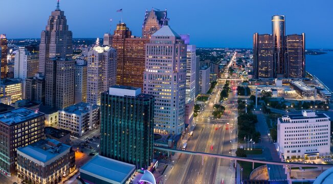 Detroit skyline at twilight, illuminated skyscrapers, busy city streets. Urban cityscape at night. DOWNTOWN, DETROIT, MICHIGAN, UNITED STATES - Powered by Adobe