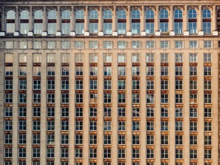 Architectural detail of a large, light beige brick building with numerous evenly spaced windows. Classic design, showcasing urban texture. MICHIGAN CENTRAL, DETROIT, MICHIGAN, UNITED STATES