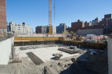 Urban construction site with foundation, crane, and workers.