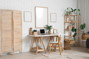 Blank posters and workplace with laptop in living room