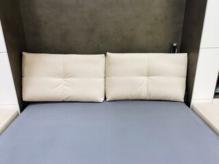 There is a cozy bed that features two pristine white pillows resting comfortably on it along with a vibrant blue mattress, creating an inviting and serene atmosphere in the bedroom
