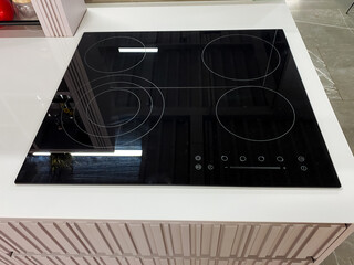A sleek black stove top oven is elegantly positioned on a pristine white countertop, adding a...