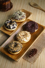 several donuts with chocolate topping, tiramisu, peanut cheese and sprinkles, on a wooden base, photographed with studio light with a wooden theme