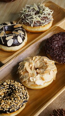 several donuts with chocolate topping, tiramisu, peanut cheese and sprinkles, on a wooden base, photographed with studio light with a wooden theme