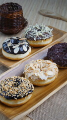 several donuts with chocolate topping, tiramisu, peanut cheese and sprinkles, on a wooden base, photographed with studio light with a wooden theme