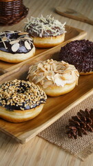 several donuts with chocolate topping, tiramisu, peanut cheese and sprinkles, on a wooden base, photographed with studio light with a wooden theme