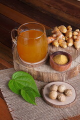herbal drink made from turmeric, betel leaves and oak galls photographed in a studio setting with traditional Indonesian theme props