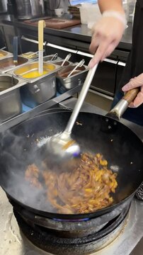 vertical video, wok cooking, making Thai stir fried noodles (pad see ew)
