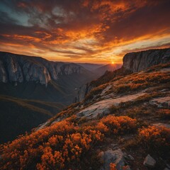 A dramatic mountain cliff against a vibrant orange sunset.