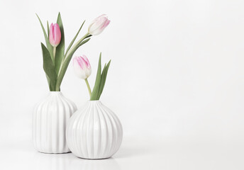 Two white textured vases with tulip flowers