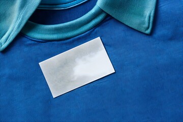 Fototapeta premium Elegant Blank White Laundry Care Clothes Label on Blue Shirt for Professional and Stylish Presentation
