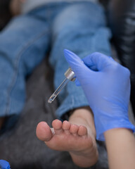 Pregnant woman getting a pedicure in a beauty salon. The technician applies moisturizing oil to the...